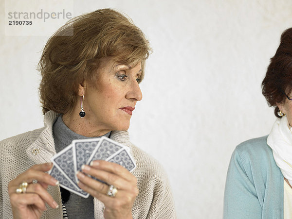 Zwei ältere Frauen spielen Karten  eine schaut über die Schulter