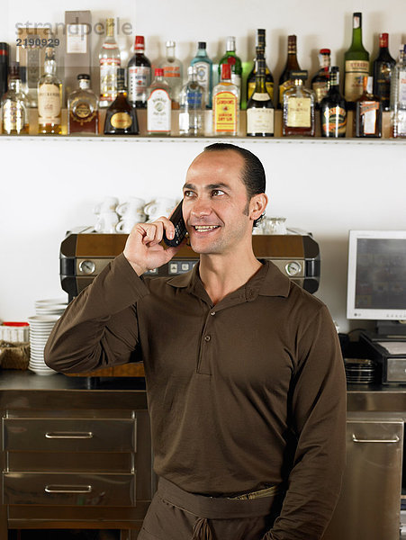 Barkeeper am Telefon vor der Kaffeemaschine.