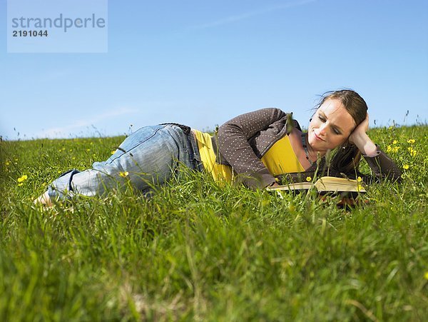 Junge Frau im Gras liegend.