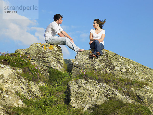 Junges Paar auf einem großen Felsen.