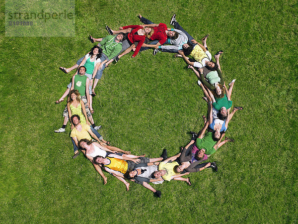 Gruppe im Kreis auf Gras liegend