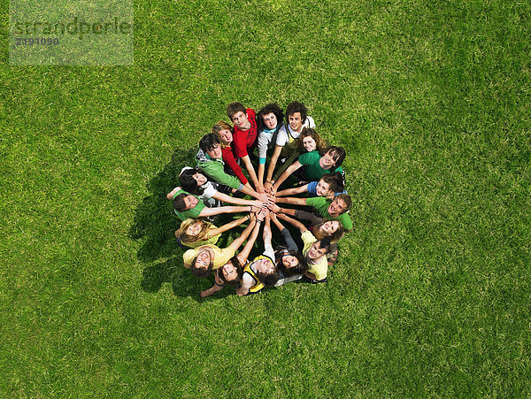 Gruppe steht im Kreis auf Gras