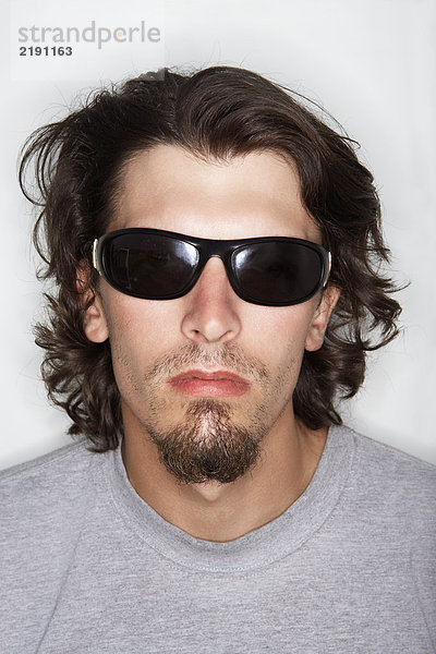 Junger Mann mit langen Haaren und Sonnenbrille