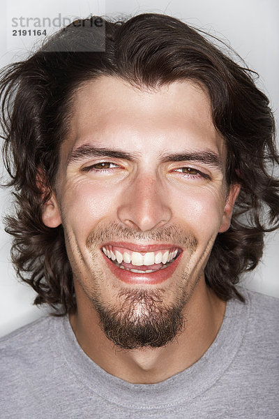 Junger Mann mit langen Haaren lächelnd