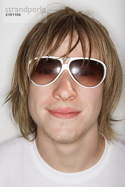 Junger Mann lächelt mit Sonnenbrille