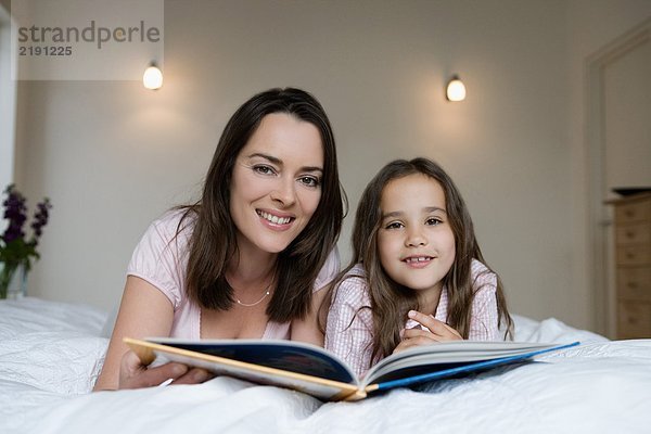 Mutter und Tochter sitzen auf einem Bett.