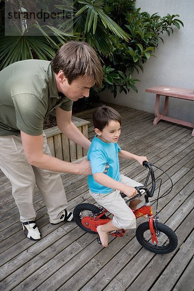 Ein Junge  der mit seinem Vater Fahrrad fährt.