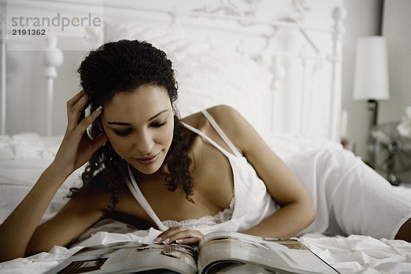 Frau liest Magazin auf dem Bett.