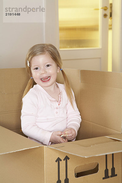 Mädchen (3-5) stehend im Karton lächelnd  Portrait