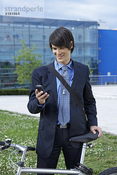 Geschäftsmann mit Fahrrad und Blick aufs Handy.