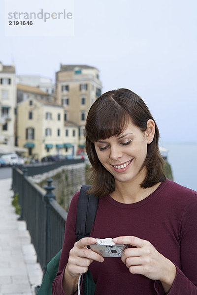 Porträt einer jungen Frau mit Kamera und Blick auf die lächelnde Altstadt im Hintergrund.