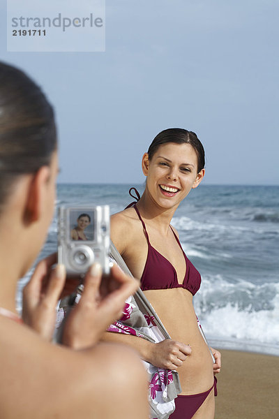 Zwei junge Frauen am Strand beim Fotografieren.