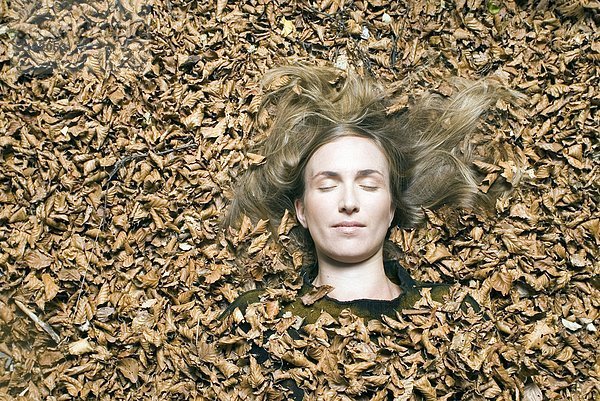 Junge Frau auf Blättern liegend.