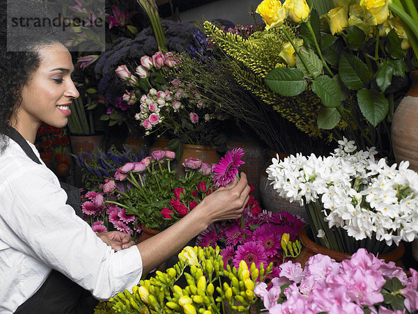 Junge Floristin bei der Auswahl der Blume  lächelnd  Profil