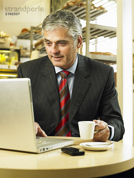 Reife Geschäftsleute sitzen im Cafe mit Laptop