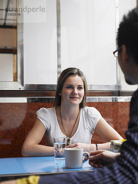 Junge Frau sitzend im Café mit Mann  lächelnd