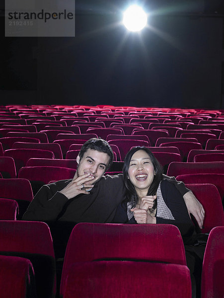 Junges Paar sitzt im leeren Kino und lacht  Porträt
