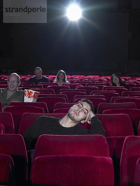 Junger Mann schläft im Kino