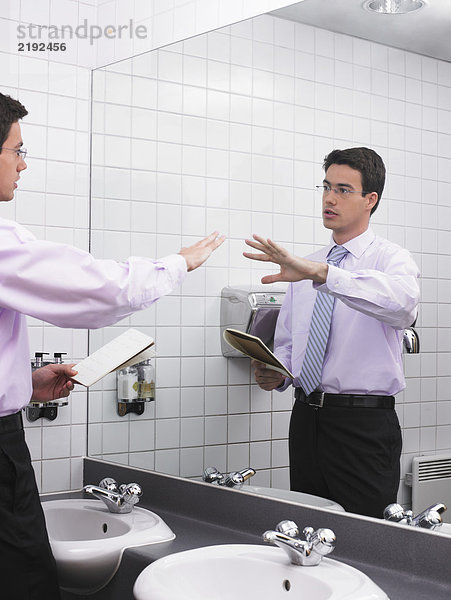 Mann beim Sprechen im Büro-Waschraumspiegel