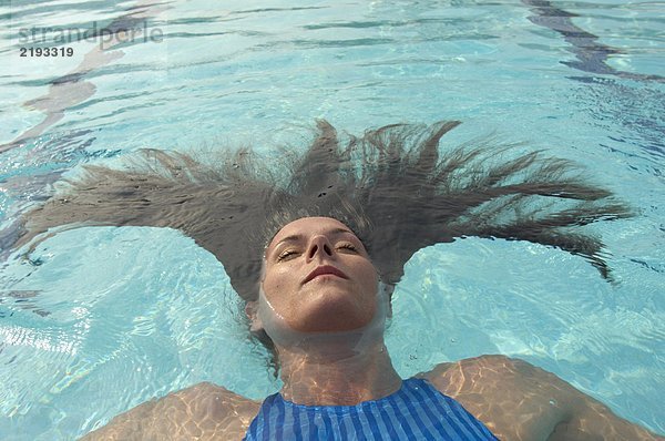 Frau mit langen Haaren im Schwimmbad schwimmend  Augen geschlossen