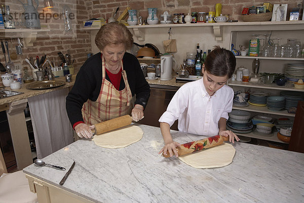 Seniorin und Enkelin (9-11) beim Gebäckrollen in der Küche