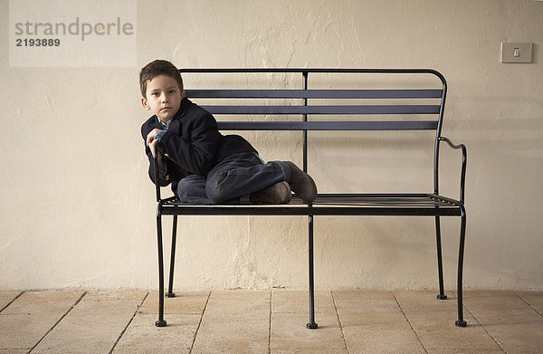 Junge (4-6) sitzend auf Bank im Freien  Portrait