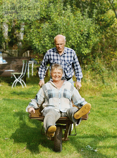 Älterer Mann mit Frau in Schubkarre