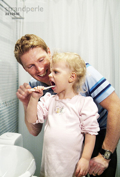 Papa hilft Tochter beim Zähneputzen
