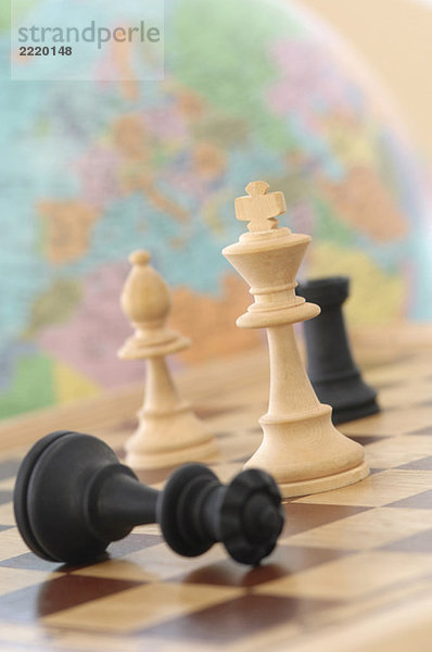 Schachfiguren mit Globus im Hintergrund