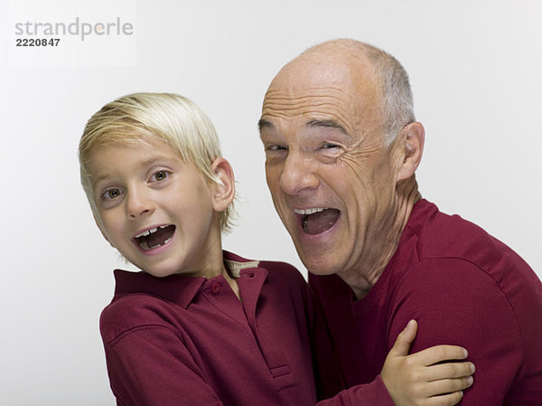 Enkel (8-9) umarmt Großvater  lächelnd  Portrait