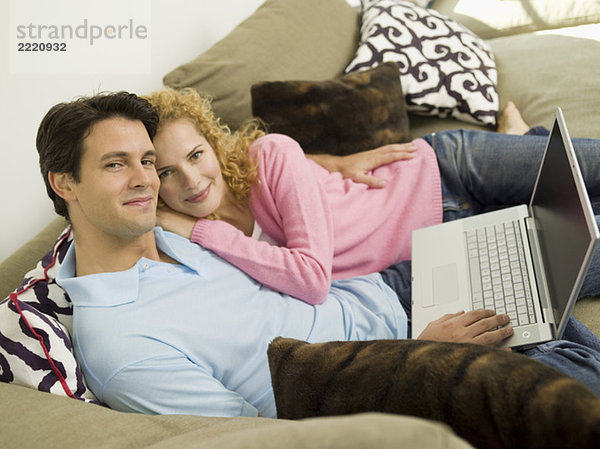 Junges Paar auf dem Sofa mit Laptop  lächelnd