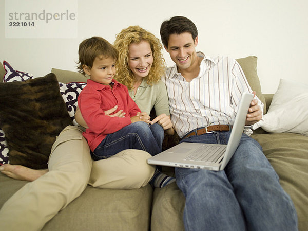 Young family in living room  father using laptop