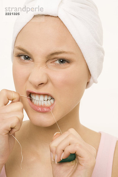 Nahaufnahme einer jungen Frau  die ihre Zähne mit Zahnseide pflegt.