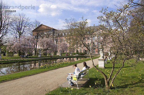 Zwei Frauen sitzen auf Bank in der Nähe von Pool vor Palace  Kurfuerstliches Palais  Trier  Deutschland