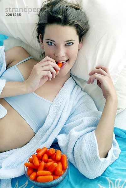 Frau im Bett Karotten Essen