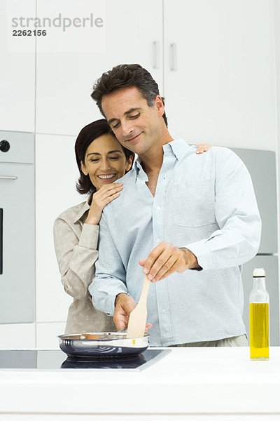 Paar Kochen zusammen in der Küche  Frau lehnt Kopf auf die Schulter des Mannes  beide mit Blick nach unten