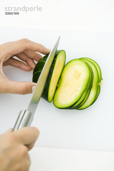 Hände schneiden Sommerkürbis (zapallito redondo)  mit Messer  Schnittansicht