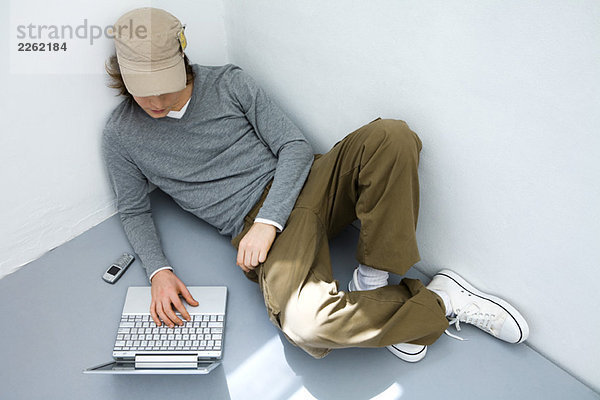 Junger Mann auf dem Boden sitzend  mit Laptop-Computer  hoher Blickwinkel