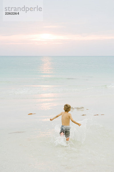 Kleiner Junge läuft am Strand  Arme ausstrecken  Rückansicht