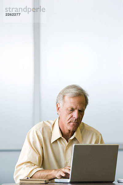 Mann sitzend  mit Laptop-Computer  nach unten schauend