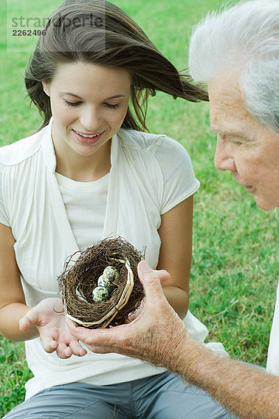 Großvater und jugendliche Enkelin beim gemeinsamen Betrachten des Vogelnestes  Schnittansicht