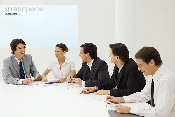 Gruppe von Geschäftspartnern sitzt zusammen am Konferenztisch  lächelnd