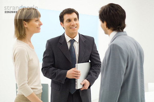 Drei Geschäftspartner stehen  reden miteinander  lächeln