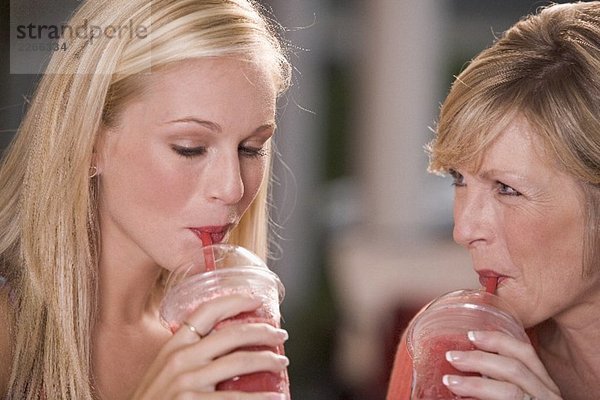 Junge und ältere Frau trinken Frozen Strawberry Smoothie