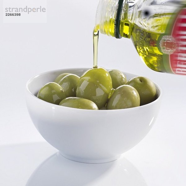 Olivenöl über Oliven giessen