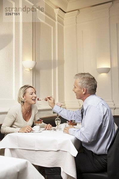 Mann füttert Frau mit Dessert in einem Restaurant