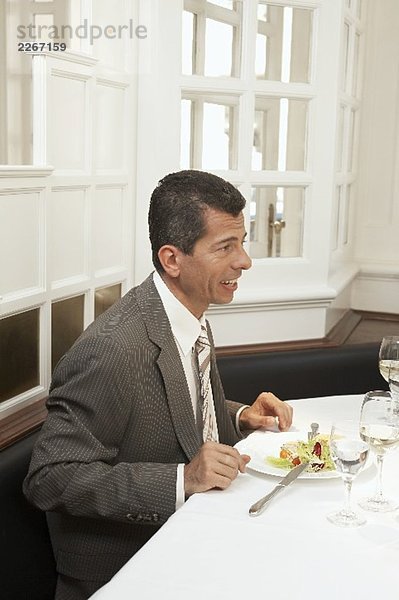 Mann sitzt im Restaurant vor einem Salatteller