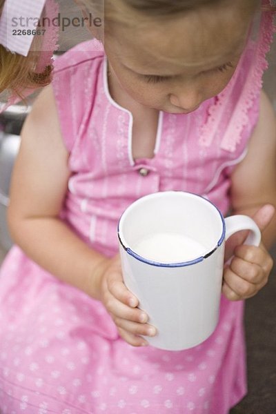 Kleines Mädchen hält Becher Milch