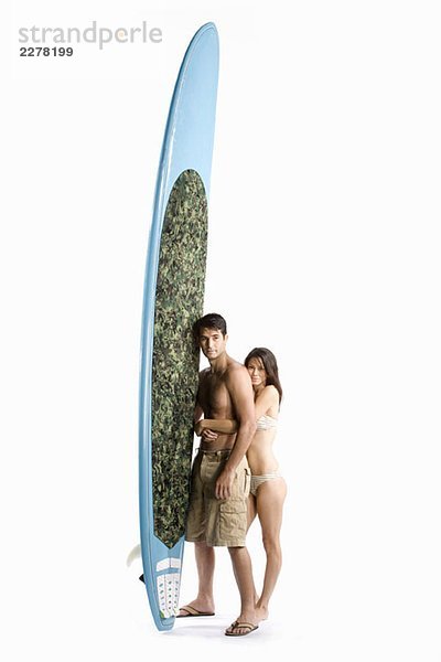 Ein Paar steht mit einem Surfbrett.
