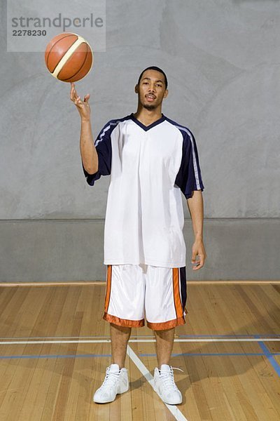 Ein junger Mann  der einen Basketball auf dem Finger spinnt.